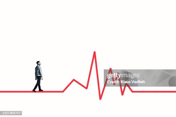 side view of young man walking on red line graph - pulse trace stockfoto's en -beelden