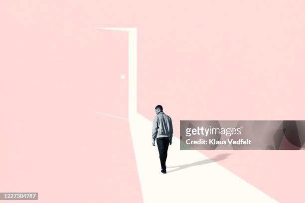 sad young man walking towards ajar door - opportunity stock pictures, royalty-free photos & images