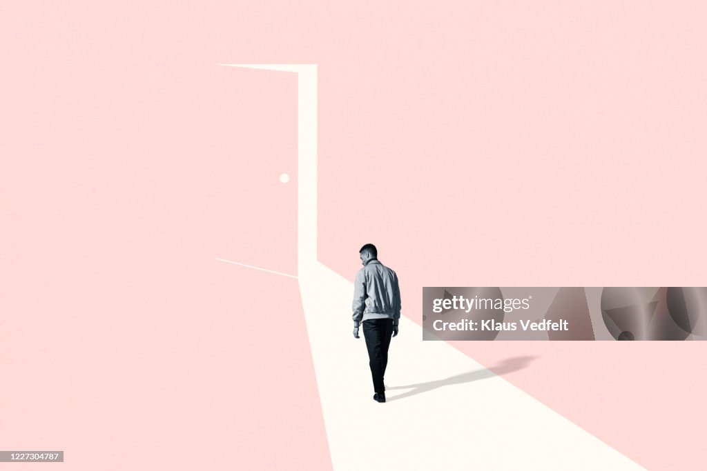 Sad young man walking towards ajar door