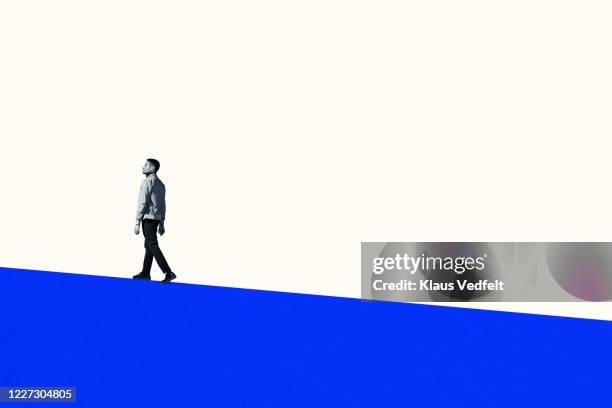 full length of young man walking on blue hill - finding hope stock pictures, royalty-free photos & images