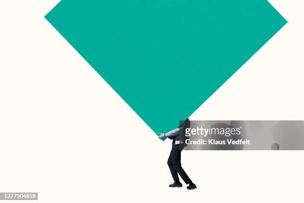 low section of man carrying large green block - balancing act stockfoto's en -beelden