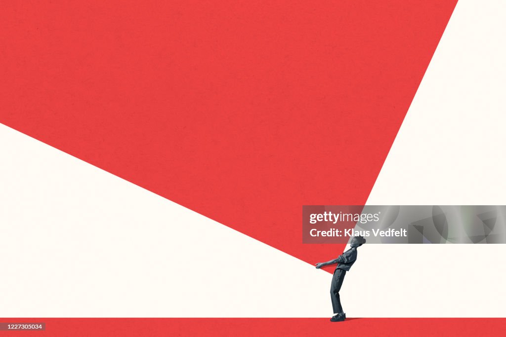 Side view of young woman carrying large red block