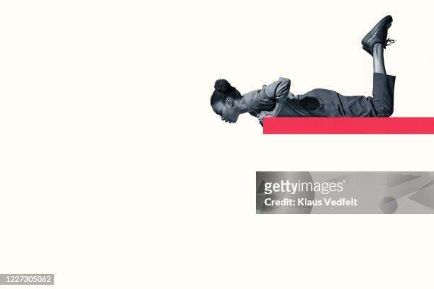young woman lying on red ramp while looking down - neugierde stock-fotos und bilder