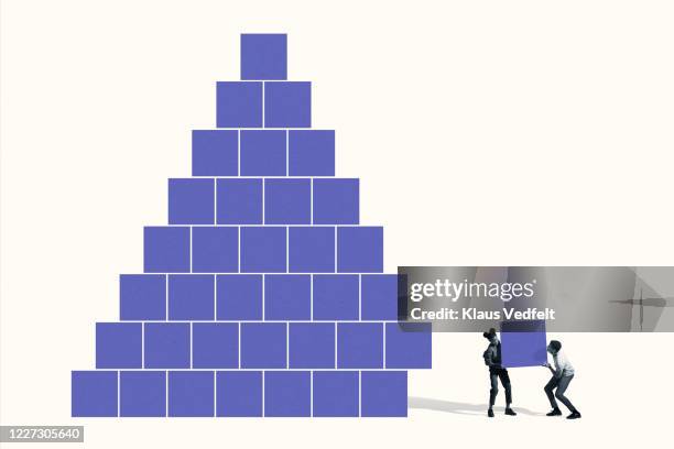 man and woman building pyramid with blue blocks - building blocks concept stock-fotos und bilder