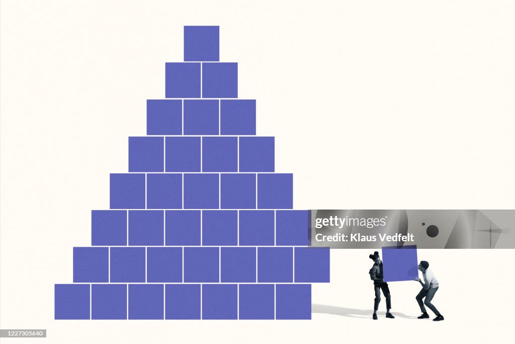 Man and woman building pyramid with blue blocks