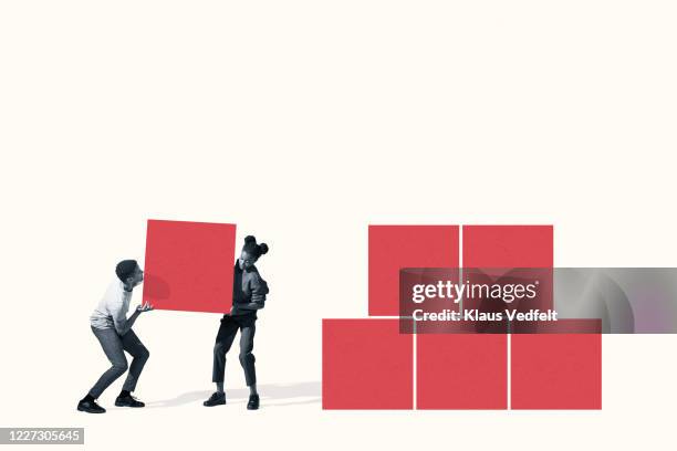 young man and woman carrying red block - team building activity stockfoto's en -beelden