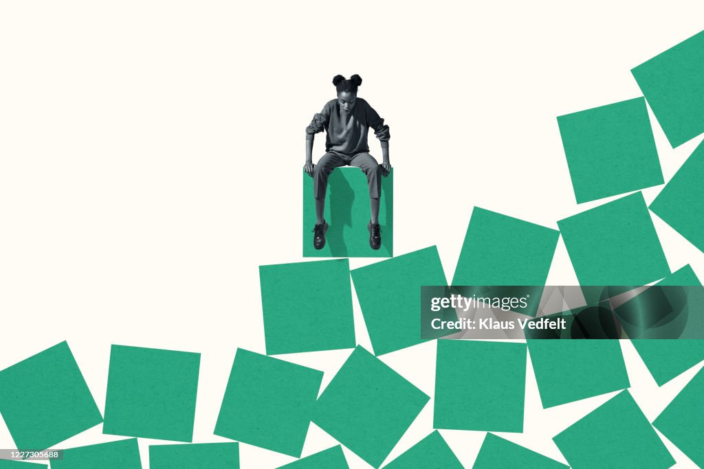 Woman looking down while sitting on green block