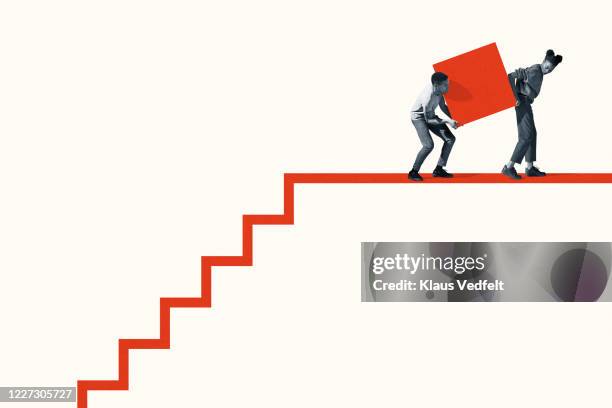 woman and man carrying large block on staircase - 2 steps stock-fotos und bilder