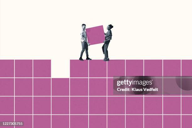 smiling woman and man carrying pink block on grid - team building activity stockfoto's en -beelden