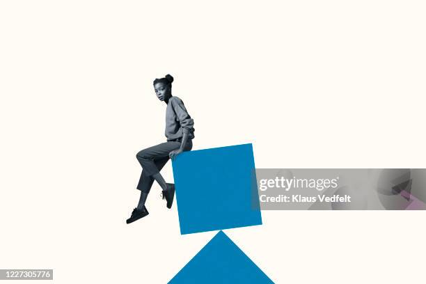 portrait of scared woman sitting on blue block - balancing act fotografías e imágenes de stock