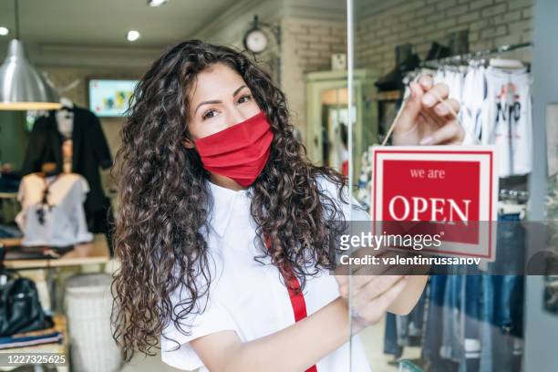 happy business owner hanging an open sign during covid-19 - opening event stock pictures, royalty-free photos & images