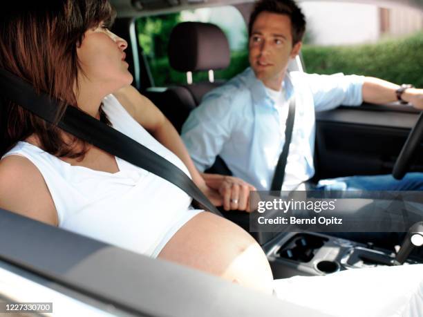 pregnant woman sits in a car - her husband holds her hand. - pregnant woman car stock pictures, royalty-free photos & images