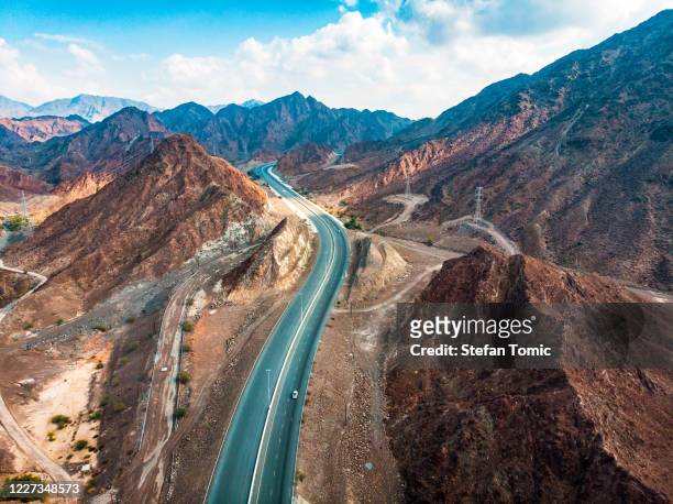desert road through hajar mountain range stretching through uae - desert mountain range stock pictures, royalty-free photos & images