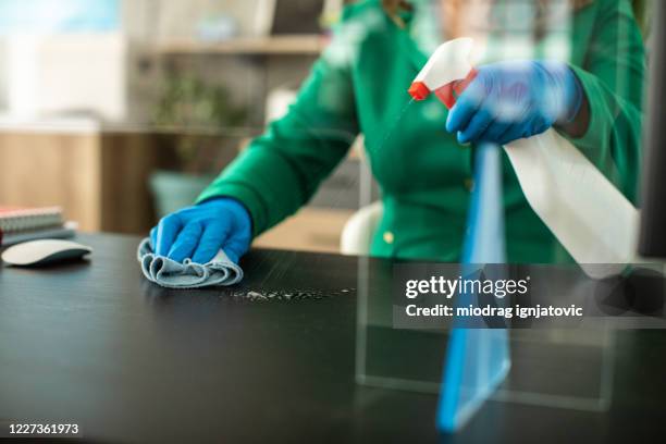 bank manager disinfecting desk in office - sneeze guard stock pictures, royalty-free photos & images