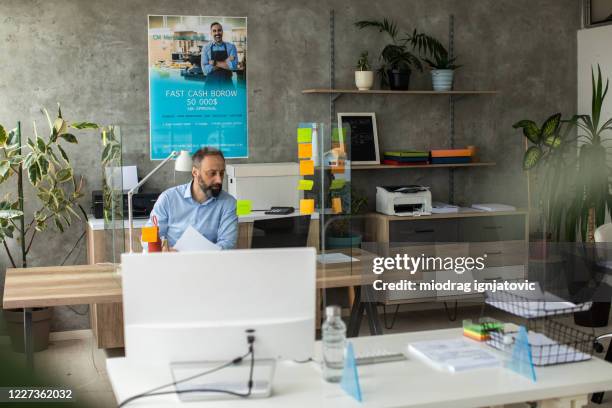 mann arbeitet allein in bankfiliale - die neue normalität stock-fotos und bilder