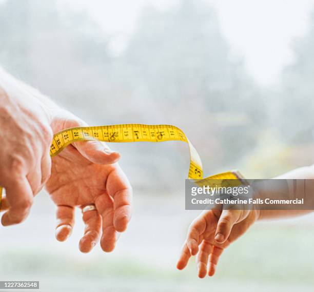 hands reaching for a measuring tape - centimeter stock pictures, royalty-free photos & images