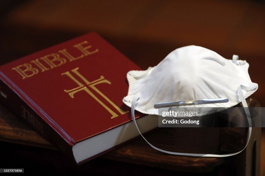 Bible in a church with a disposable mask to avoid contagious coronavirus.