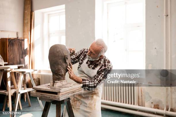 uomo anziano che fa statua d'argilla modellando un viso con lo strumento di lavoro - sculpture foto e immagini stock