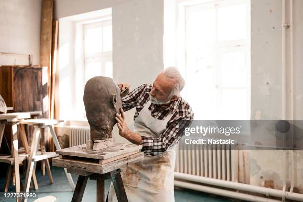 senior man making statue of clay shaping a face with work tool - passion work stock pictures, royalty-free photos & images