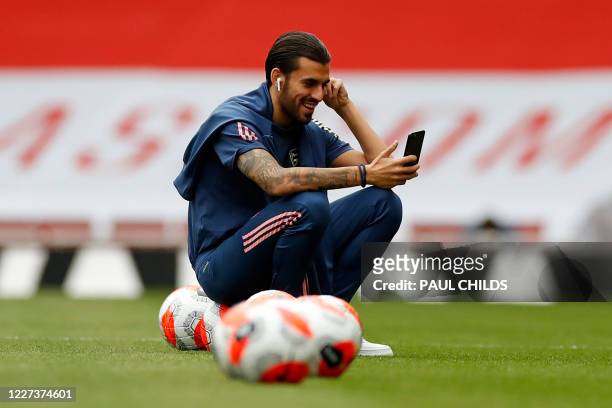 Arsenal's Spanish midfielder Dani Ceballos smiles as he checks his phone on the pitch ahead of the English Premier League football match between...