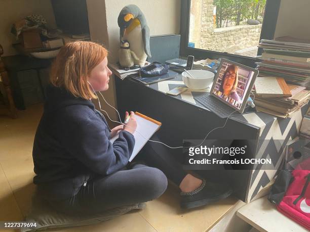 Une élève de première suit un cours en télé enseignement sur son ordinateur dans sa chambre suite au confinement instauré pour lutter contre la...