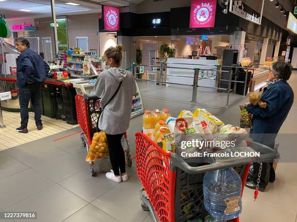 Consommateurs faisant la queue, une femme porte un masque pour se protéger contre le Covid-19 lors du passage en caisse au supermarché Auchan de...