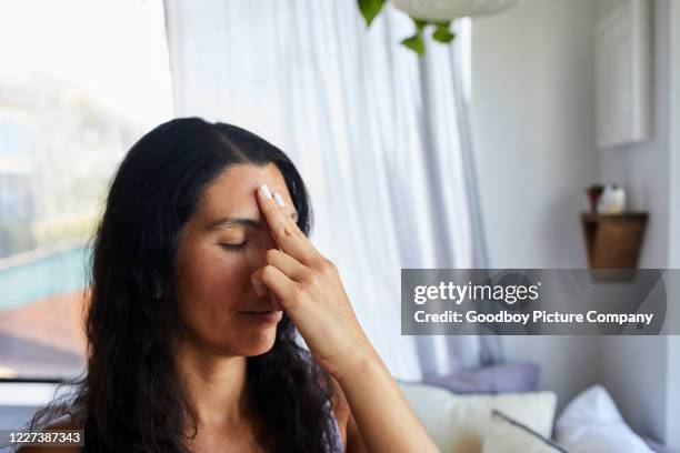 woman touching her forehead chakra during a meditation session at home - chakras stock pictures, royalty-free photos & images