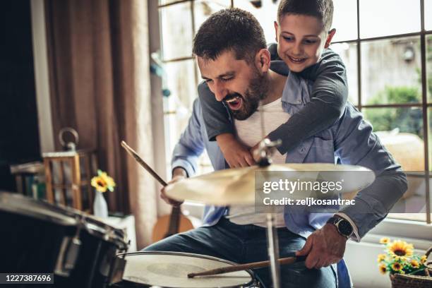 padre e hijo tocando instrumentos musicales en casa - playing drums fotografías e imágenes de stock