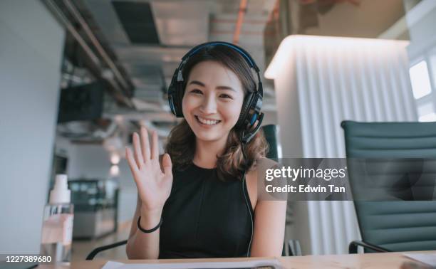 een aziatische chinese mooie vrouwen witte boordenarbeider die aan de video die videoconferentie van de camera roept met zijn bedrijfspartners met gezichtsmasker spreekt - chinese people posing for camera stockfoto's en -beelden