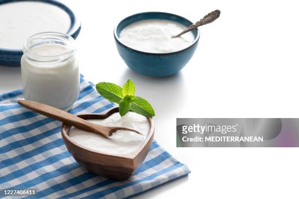homemade yogurt heart shape wooden bowl with mint leaves and glass container isolated on white - yogurt container stock pictures, royalty-free photos & images