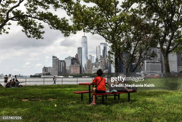 People relax with a view of lower Manhattan in the background on Governors Island on July 15, 2020 in New York City. Governors Island reopens to...