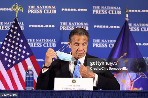 New York Governor Andrew Cuomo removes his face mask at the start of a news conference at the National Press Club May 27, 2020 in Washington, DC....