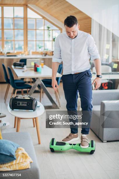 homem montando hoverboard em casa na sala de estar - hoverboard - fotografias e filmes do acervo