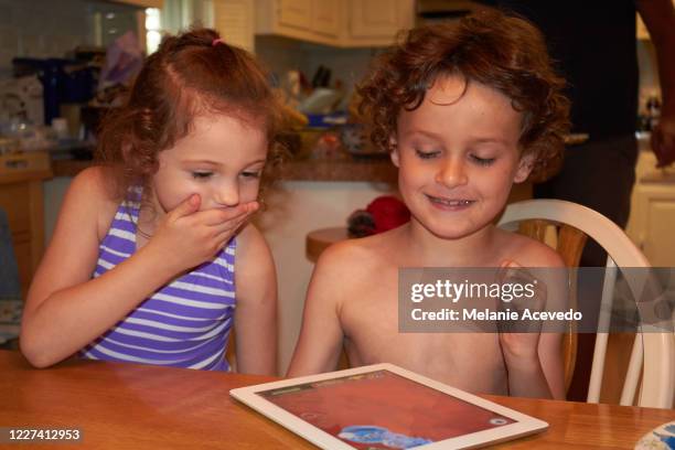 close up shot of a little boy and girl sitting at a kitchen table playing together on a digital tablet. - melanie cousins - fotografias e filmes do acervo