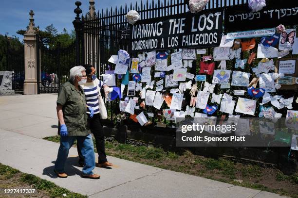 People walk by a memorial for those who have died from the coronavirus outside Green-Wood Cemetery on May 27, 2020 in the Brooklyn borough of New...