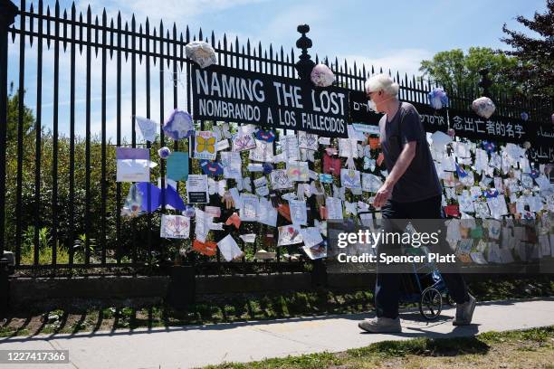Man walks by a memorial for those who have died from the coronavirus outside Green-Wood Cemetery on May 27, 2020 in the Brooklyn borough of New York...