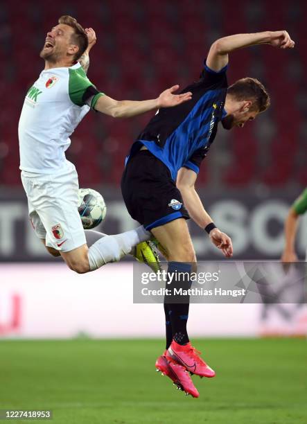 Daniel Baier of Augsburg jumps for a header with Dennis Srbeny of Paderborn during the Bundesliga match between FC Augsburg and SC Paderborn 07 at...