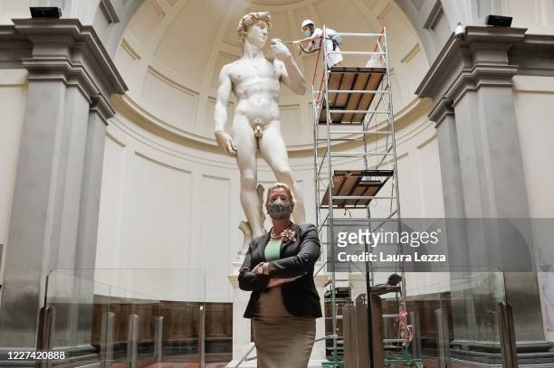 The Director of the Galleria dell'Accademia Cecilie Hollberg wearing a protective mask poses for a photo while a restorer cleans Michelangelo's David...