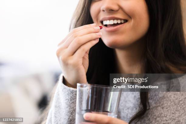 mulher sorridente toma vitamina diária - tomando remédio - fotografias e filmes do acervo