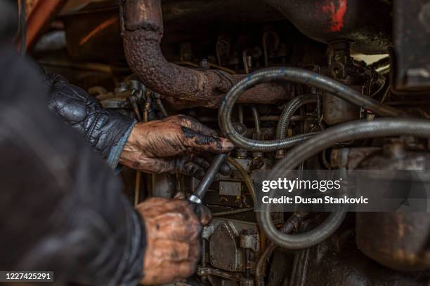 ein älterer amerikanischer lkw-fahrer repariert eine maschine - grease stock-fotos und bilder