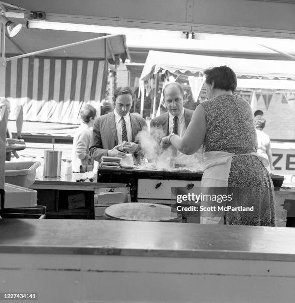 View of a woman preparing food for a pair of customers at a booth on Mulberry Street during the Feast Of San Gennaro Festival, in the Little Italy...