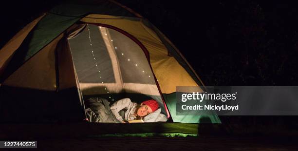 mujer leyendo por la noche en tienda - tienda de campaña fotografías e imágenes de stock