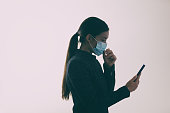 COVID-19 mask wearing woman touching her face while walking and texting mobile phone, Coronavirus prevention not properly using the protection