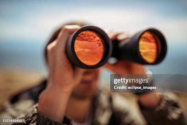 mens die door verrekijkers kijkt - verrekijker stockfoto's en -beelden
