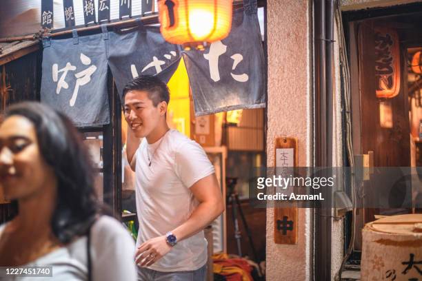 young mixed race woman and japanese man leaving izakaya - leaving restaurant stock pictures, royalty-free photos & images