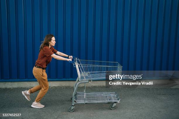 woman pushing shopping cart - shopping trolleys stockfoto's en -beelden