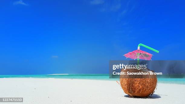 coconut juice with pink parasol over white sand of tropical beach. summer concept. copy space - cocktail umbrella stock pictures, royalty-free photos & images