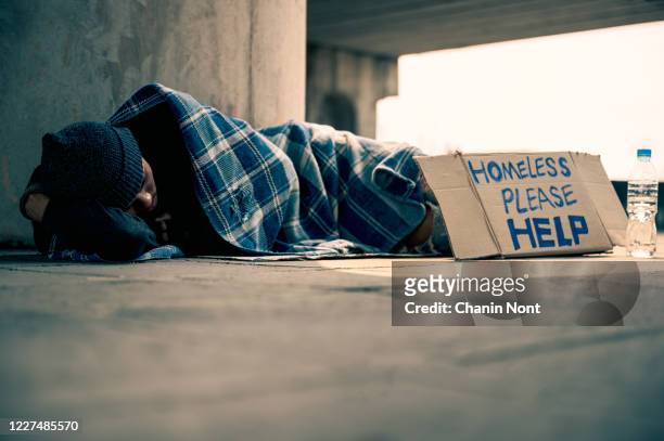 homeless man sleeping on cardboard - homelessness stockfoto's en -beelden