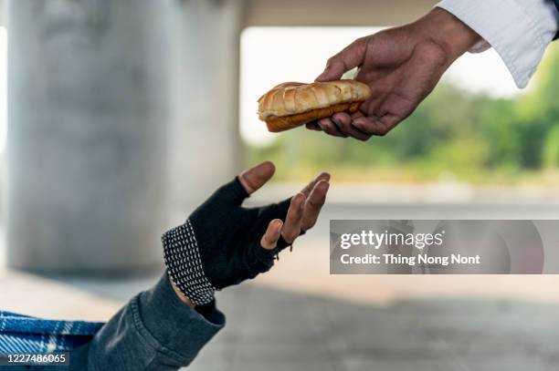 cropped hands holding bread - homeless person - fotografias e filmes do acervo