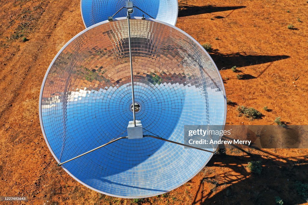 Solar Thermal Power Station with parabolic dish reflector in red dirt field, outback Australia
